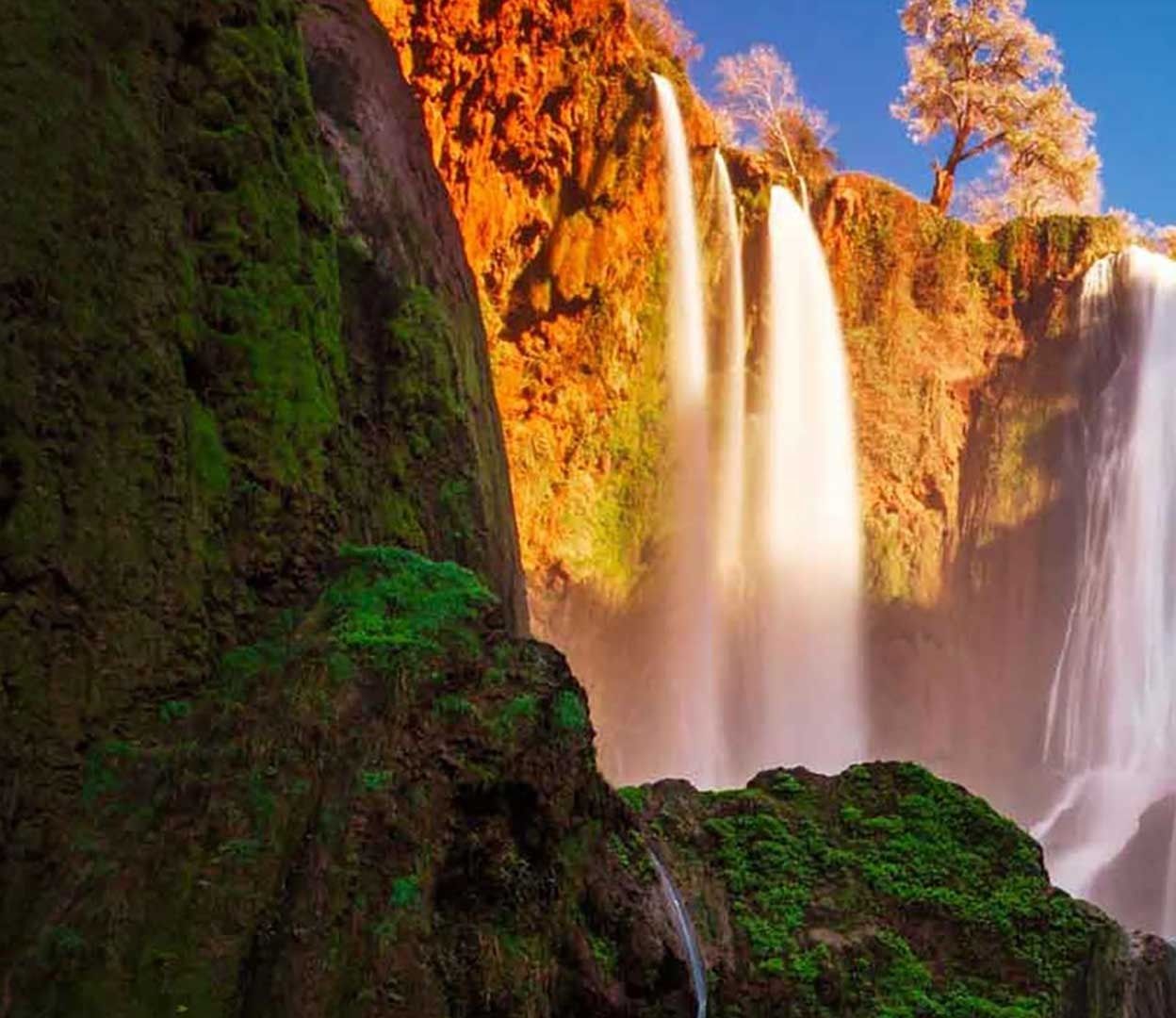 Red limestone cliffs and the first streams of the Ouzoud Waterfalls in the evening light