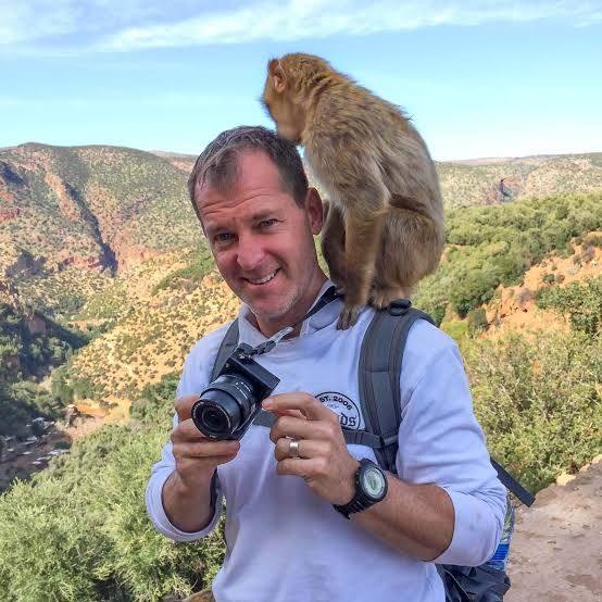 Visiteur avec un appareil photo et un macaque de Barbarie près d'Ouzoud